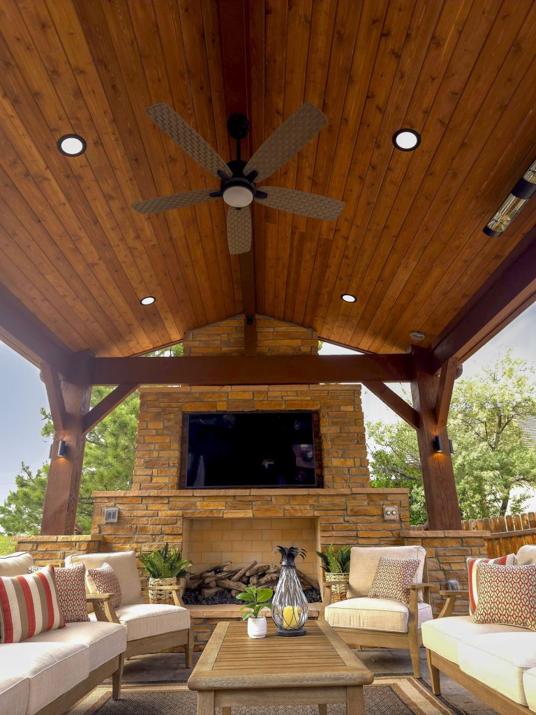 Wooden outdoor patio with ceiling fan, recessed lighting, fireplace, comfortable seating, and views of surrounding trees