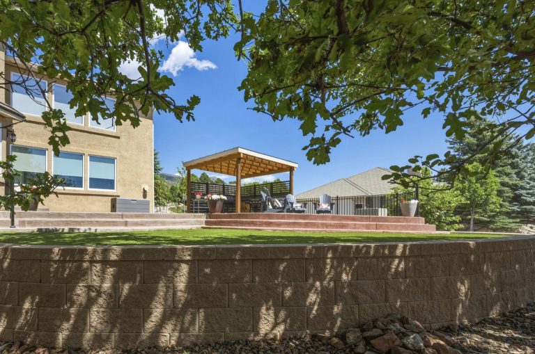 School playground with yellow shade structure, modern building, and brick wall in foreground under blue sky