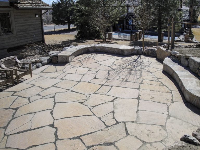 Newly installed flagstone patio with irregular cut stones and mortar joints in a residential backyard