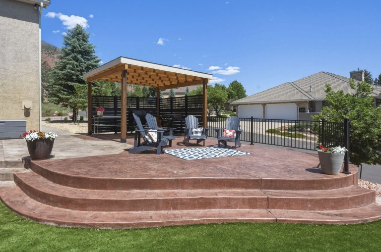 Backyard patio with curved brick seating area, wooden pergola, lounge chairs, and mountain views