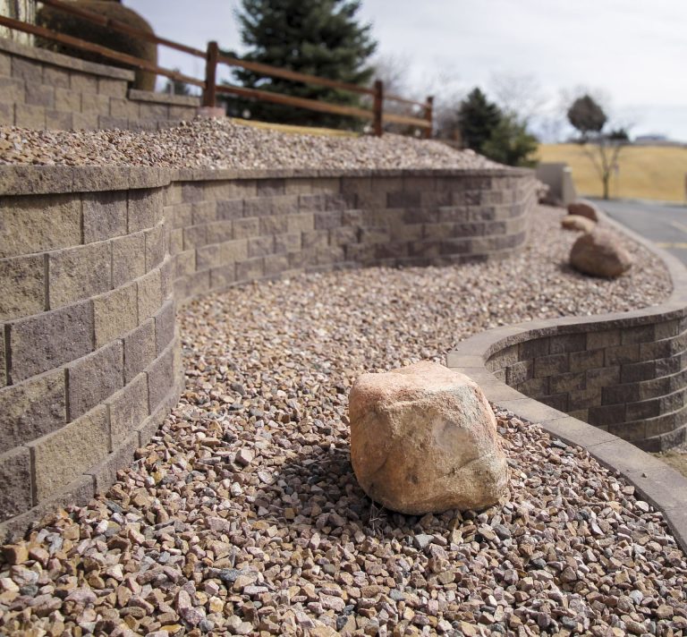 Retaining wall made of concrete blocks with gravel base and landscaping stones in a residential yard