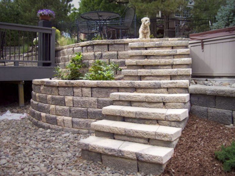 Curved outdoor stone steps leading up to a residential patio area with landscaping and metal railings