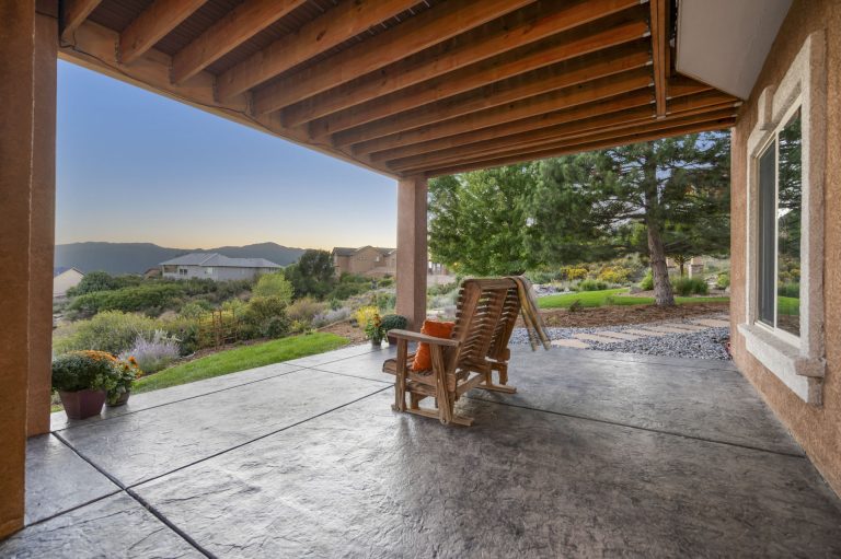 Covered patio with wooden beams overlooking rolling hills and vineyards with two wooden chairs