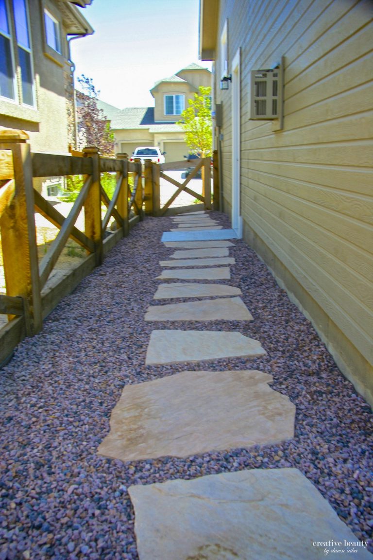 Paved stepping stones leading through gravel pathway between yellow and cream colored beach houses