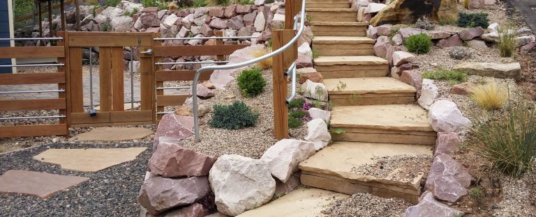 Stepped garden pathway with large rocks and desert landscaping beside wooden structures