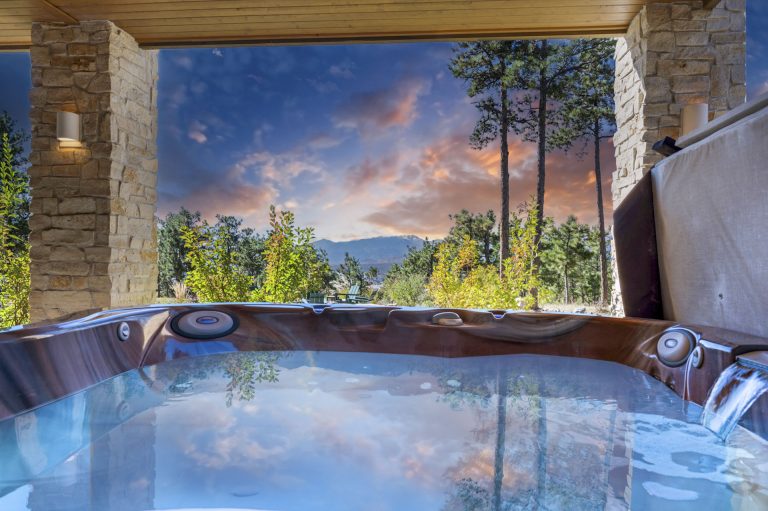Luxurious indoor hot spring bath with mountain and forest views framed by stone architecture