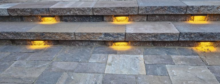 Yellow ground lights embedded in stone pavement steps at dusk or night