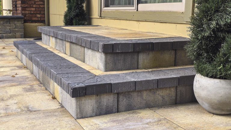 Modern outdoor patio with two-tier concrete block retaining walls and paved stone flooring