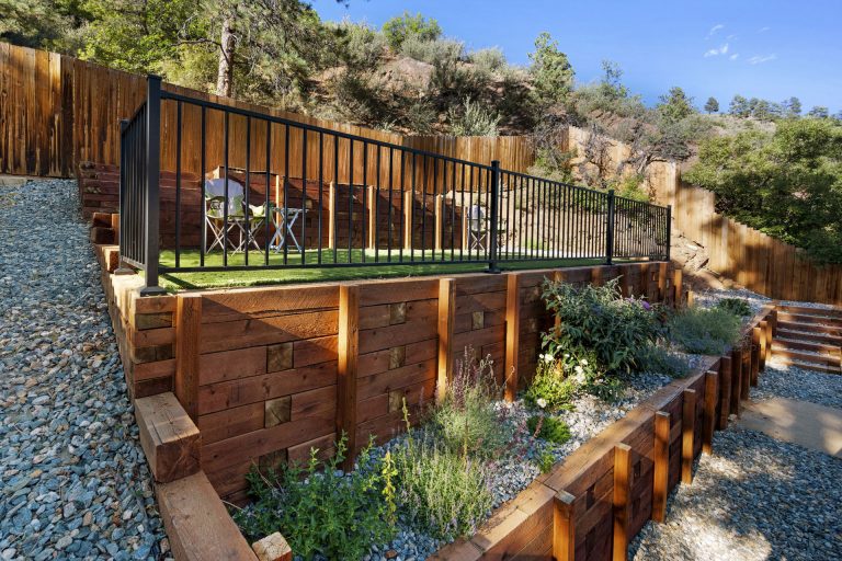 Modern elevated wooden deck with metal railings overlooking a landscaped garden with native plants and gravel pathways