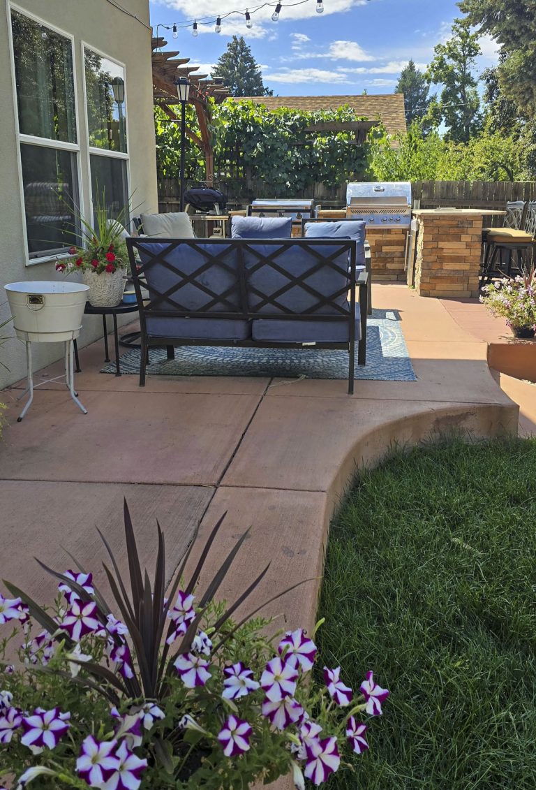 Backyard patio with seating area, purple flowers, mountain view, and manicured lawn
