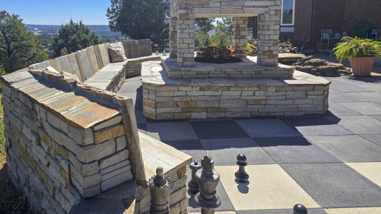 Rooftop terrace with curved stone seating walls, paved flooring, and brick building structures under clear sky